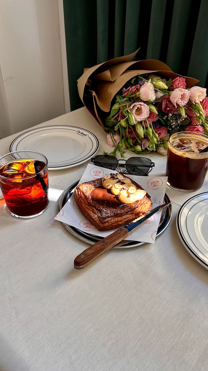 A stylish table setup with pastries, drinks, and a bouquet for a chic brunch.