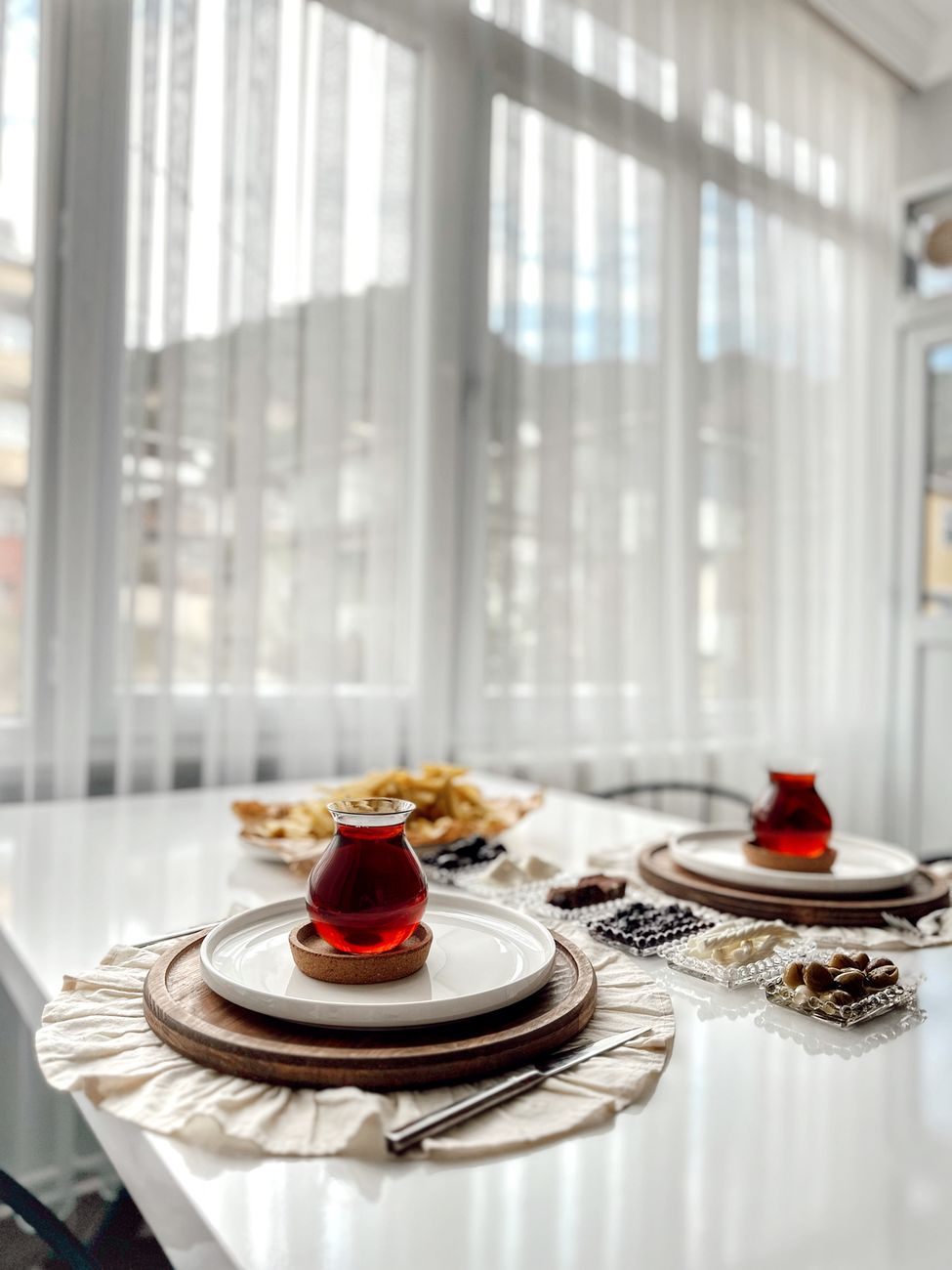 Stylish table setting with tea cups and snacks by a sunlit window for a cozy vibe.